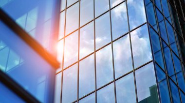 Yapısal cam duvar mavi gökyüzünü yansıtıyor. Soyut modern mimari parçası. Binanın şeffaf yüzüyle cam bina ve mavi gökyüzü. Çağdaş mimari arka plan.