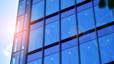 Yapısal cam duvar mavi gökyüzünü yansıtıyor. Soyut modern mimari parçası. Binanın şeffaf yüzüyle cam bina ve mavi gökyüzü. Çağdaş mimari arka plan.