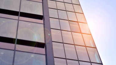 Yapısal cam duvar mavi gökyüzünü yansıtıyor. Soyut modern mimari parçası. Binanın şeffaf yüzüyle cam bina ve mavi gökyüzü. Çağdaş mimari arka plan.