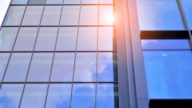 Yapısal cam duvar mavi gökyüzünü yansıtıyor. Soyut modern mimari parçası. Binanın şeffaf yüzüyle cam bina ve mavi gökyüzü. Çağdaş mimari arka plan.