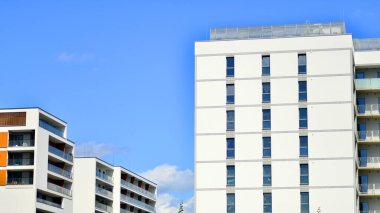 Mavi gökyüzü olan güneşli bir günde modern apartman binaları. Modern bir apartmanın cephesi