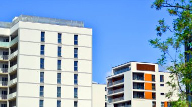 Yeşil yerleşim bölgesinde yeni daireleri olan modern bir yerleşim yeri. Çevre mimarisi. Yeşil ağaç ve yeni apartman. Doğanın ve modernliğin ahengi.