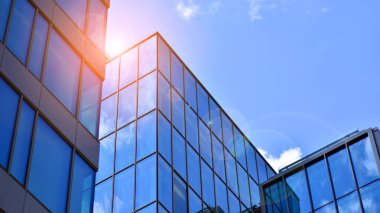 Yapısal cam duvar mavi gökyüzünü yansıtıyor. Soyut modern mimari parçası. Binanın şeffaf yüzüyle cam bina ve mavi gökyüzü. Çağdaş mimari arka plan.