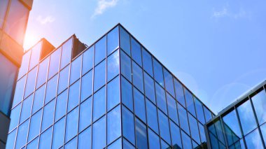 Yapısal cam duvar mavi gökyüzünü yansıtıyor. Soyut modern mimari parçası. Binanın şeffaf yüzüyle cam bina ve mavi gökyüzü. Çağdaş mimari arka plan.