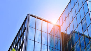 Yapısal cam duvar mavi gökyüzünü yansıtıyor. Soyut modern mimari parçası. Binanın şeffaf yüzüyle cam bina ve mavi gökyüzü. Çağdaş mimari arka plan.