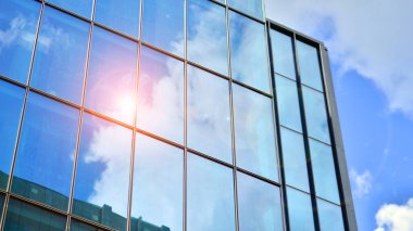 Yapısal cam duvar mavi gökyüzünü yansıtıyor. Soyut modern mimari parçası. Binanın şeffaf yüzüyle cam bina ve mavi gökyüzü. Çağdaş mimari arka plan.