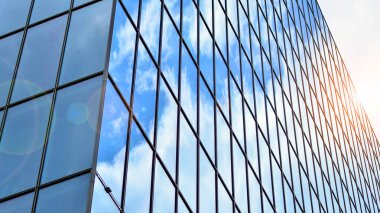 Yapısal cam duvar mavi gökyüzünü yansıtıyor. Soyut modern mimari parçası. Binanın şeffaf yüzüyle cam bina ve mavi gökyüzü. Çağdaş mimari arka plan.