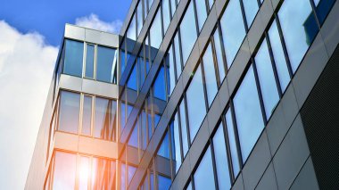 Yapısal cam duvar mavi gökyüzünü yansıtıyor. Soyut modern mimari parçası. Binanın şeffaf yüzüyle cam bina ve mavi gökyüzü. Çağdaş mimari arka plan.