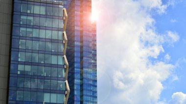 Yapısal cam duvar mavi gökyüzünü yansıtıyor. Soyut modern mimari parçası. Binanın şeffaf yüzüyle cam bina ve mavi gökyüzü. Çağdaş mimari arka plan.