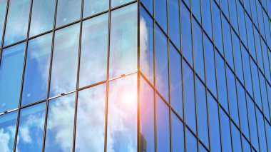 Yapısal cam duvar mavi gökyüzünü yansıtıyor. Soyut modern mimari parçası. Binanın şeffaf yüzüyle cam bina ve mavi gökyüzü. Çağdaş mimari arka plan.