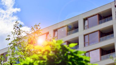 Modern residential building with new apartments in a green residential area. Eco architecture. Green tree and new apartment building. The harmony of nature and modernity.