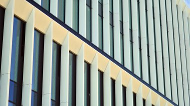 Mavi gökyüzü arka planlı cam modern bina. Görünüm ve mimari detaylar. Şehir soyutu - güneş ışığında cam ofis binasının pencereleri.