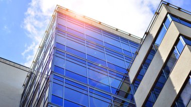 Mavi gökyüzü arka planlı cam modern bina. Görünüm ve mimari detaylar. Şehir soyutu - güneş ışığında cam ofis binasının pencereleri.