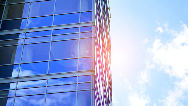 Glass modern building with blue sky background. View and architecture details. Urban abstract - windows of glass office building in  sunlight day.