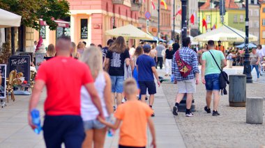 Varşova, Polonya. 29 Temmuz 2023. Sokakta yürüyen bir sürü insan. Eski bir şehir manzarasının arka planına doğru hareket eden bir kalabalık.