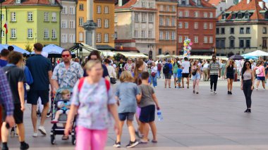 Varşova, Polonya. 29 Temmuz 2023. Sokakta yürüyen bir sürü insan. Eski bir şehir manzarasının arka planına doğru hareket eden bir kalabalık.