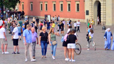 Varşova, Polonya. 29 Temmuz 2023. Sokakta yürüyen bir sürü insan. Eski bir şehir manzarasının arka planına doğru hareket eden bir kalabalık.