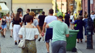 Varşova, Polonya. 29 Temmuz 2023. Sokakta yürüyen bir sürü insan. Eski bir şehir manzarasının arka planına doğru hareket eden bir kalabalık.