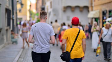 Varşova, Polonya. 29 Temmuz 2023. Sokakta yürüyen bir sürü insan. Eski bir şehir manzarasının arka planına doğru hareket eden bir kalabalık.