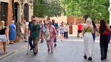 Varşova, Polonya. 29 Temmuz 2023. Sokakta yürüyen bir sürü insan. Eski bir şehir manzarasının arka planına doğru hareket eden bir kalabalık.