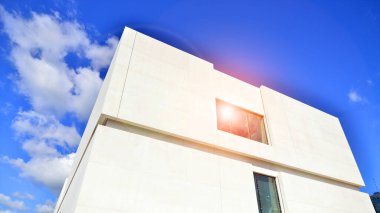 Mavi gökyüzüne karşı modern beyaz beton bina duvarları.