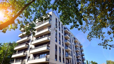 Modern apartman ve yeşil ağaçlar. Ekolojik konut mimarisi. Ağaçların çevresindeki modern bir yerleşim yeri. Kentte ekoloji ve yeşil yaşam, kentsel çevre kavramı. 