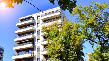 Modern apartman ve yeşil ağaçlar. Ekolojik konut mimarisi. Ağaçların çevresindeki modern bir yerleşim yeri. Kentte ekoloji ve yeşil yaşam, kentsel çevre kavramı. 