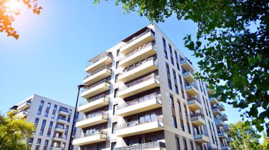 Modern apartman ve yeşil ağaçlar. Ekolojik konut mimarisi. Ağaçların çevresindeki modern bir yerleşim yeri. Kentte ekoloji ve yeşil yaşam, kentsel çevre kavramı. 