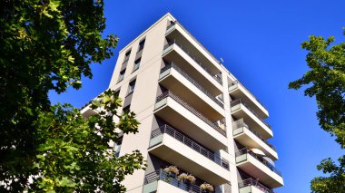 Modern apartman ve yeşil ağaçlar. Ekolojik konut mimarisi. Ağaçların çevresindeki modern bir yerleşim yeri. Kentte ekoloji ve yeşil yaşam, kentsel çevre kavramı. 