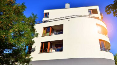 Modern apartman ve yeşil ağaçlar. Ekolojik konut mimarisi. Ağaçların çevresindeki modern bir yerleşim yeri. Kentte ekoloji ve yeşil yaşam, kentsel çevre kavramı. 