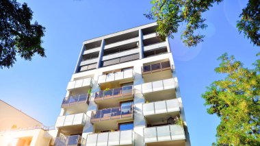Modern apartman ve yeşil ağaçlar. Ekolojik konut mimarisi. Ağaçların çevresindeki modern bir yerleşim yeri. Kentte ekoloji ve yeşil yaşam, kentsel çevre kavramı. 