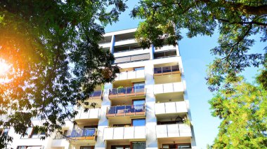 Modern apartman ve yeşil ağaçlar. Ekolojik konut mimarisi. Ağaçların çevresindeki modern bir yerleşim yeri. Ekoloji ve yeşil şehir, kentsel çevre 