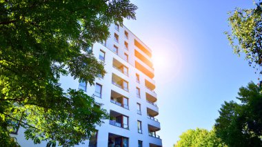 Modern apartman ve yeşil ağaçlar. Ekolojik konut mimarisi. Ağaçların çevresindeki modern bir yerleşim yeri. Ekoloji ve yeşil şehir, kentsel çevre 