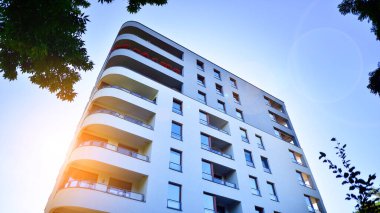 Modern apartman ve yeşil ağaçlar. Ekolojik konut mimarisi. Ağaçların çevresindeki modern bir yerleşim yeri. Ekoloji ve yeşil şehir, kentsel çevre 