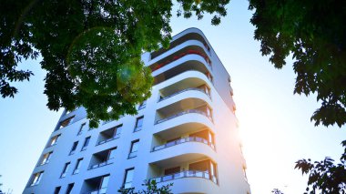 Modern apartman ve yeşil ağaçlar. Ekolojik konut mimarisi. Ağaçların çevresindeki modern bir yerleşim yeri. Ekoloji ve yeşil şehir, kentsel çevre 