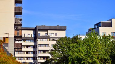Modern apartman ve yeşil ağaçlar. Ekolojik konut mimarisi. Ağaçların çevresindeki modern bir yerleşim yeri. Ekoloji ve yeşil şehir, kentsel çevre 