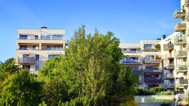 Modern apartman ve yeşil ağaçlar. Ekolojik konut mimarisi. Ağaçların çevresindeki modern bir yerleşim yeri. Ekoloji ve yeşil şehir, kentsel çevre 