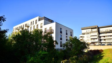 Modern apartman ve yeşil ağaçlar. Ekolojik konut mimarisi. Ağaçların çevresindeki modern bir yerleşim yeri. Ekoloji ve yeşil şehir, kentsel çevre 