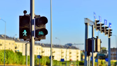 Bisiklet ikonlu yaya ve bisiklet trafiği ışığı ve yaz şehrinin arka planında aktif yeşil ışık.