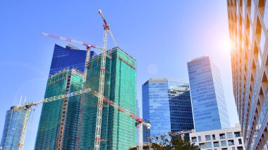 Arka planda cam gökdelenlerin yanında inşa halindeki modern yüksek binalar. 