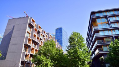 Modern apartman ve yeşil ağaçlar. Ekolojik konut mimarisi. Ağaçların çevresindeki modern bir yerleşim yeri. Ekoloji ve yeşil şehir, kentsel çevre 