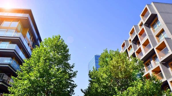 Modern apartment building and green trees. Ecological housing architecture. A modern residential building in the vicinity of trees. Ecology and green living in city, urban environment