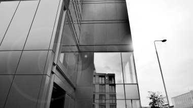 A view at a straight facade of a modern building with a dark grey facade. Dark grey metallic panel facad. Modern architectural details. Black and white.