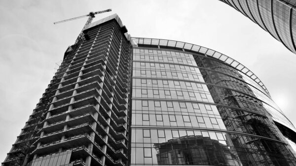 View of a skyscraper under construction. Modern architecture background. Building a high-rise building, the concept of real estate construction. Black and white.