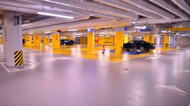 Alışveriş merkezinin altındaki yeraltı otoparkı. Aydınlatma ve sütunları olan otopark..