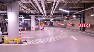 Alışveriş merkezinin altındaki yeraltı otoparkı. Aydınlatma ve sütunları olan otopark..