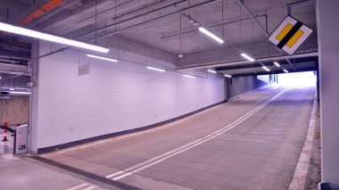 Alışveriş merkezinin altındaki yeraltı otoparkı. Aydınlatma ve sütunları olan otopark..