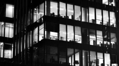 Ofis binalarının pencereleri gece aydınlandı. Cam mimari, geceleri şirket binası, iş konsepti. Siyah ve beyaz.
