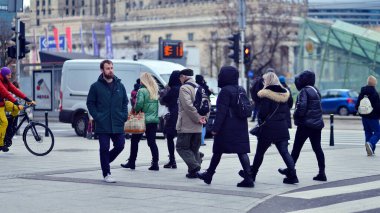 Varşova, Polonya. 29 Aralık 2023. Kalabalık kalabalık trafiğin en yoğun olduğu saatte trafik ışığı zebrasıyla karşıdan karşıya geçiyor. Europa 'da büyük bir şehirde yaşam tarzı.