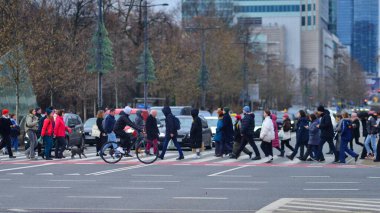 Varşova, Polonya. 29 Aralık 2023. Kalabalık kalabalık trafiğin en yoğun olduğu saatte trafik ışığı zebrasıyla karşıdan karşıya geçiyor. Europa 'da büyük bir şehirde yaşam tarzı.